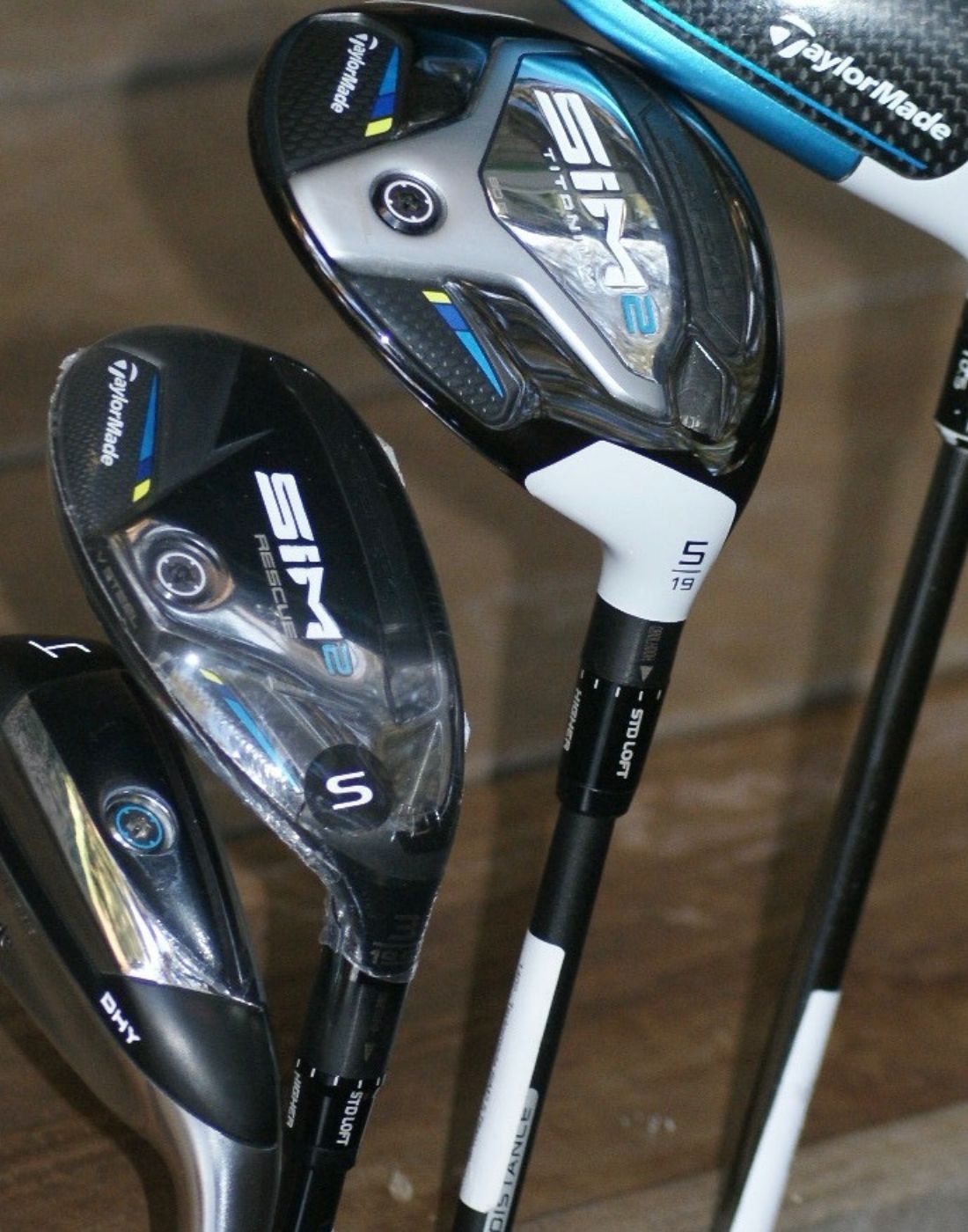 Black and blue golf club hybrids in front of a brown background.