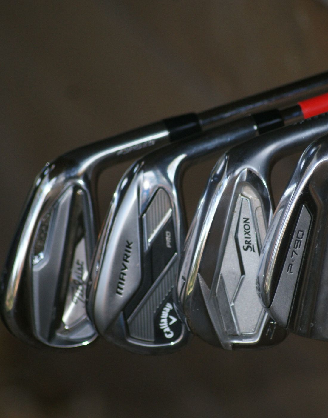 4 name brand irons in front of a brown background hanging off an edge