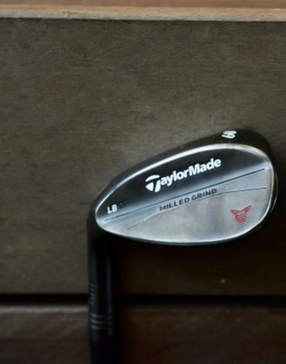 single taylormade wedge up against a brown background